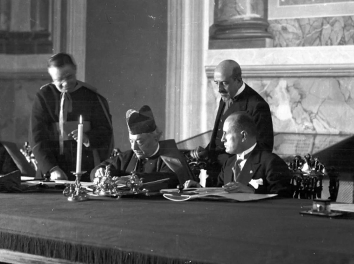 Le cardinal Gasparri signe les accords du Latran, le 11 février 1929, Mussolini assis à ses côtés.