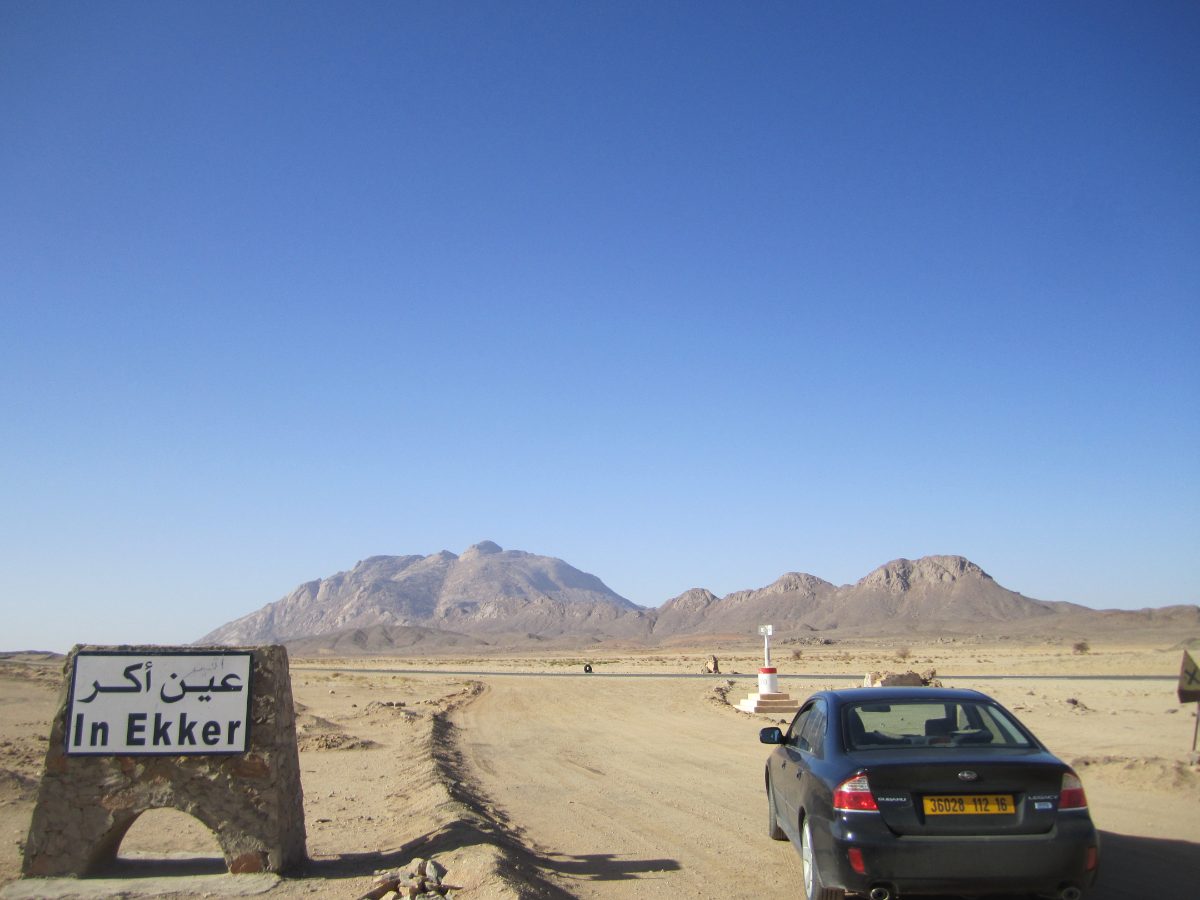 Le panneau routier d’In Ekker, dans le Hoggar algérien, devant le massif où furent menés les essais souterrains français.