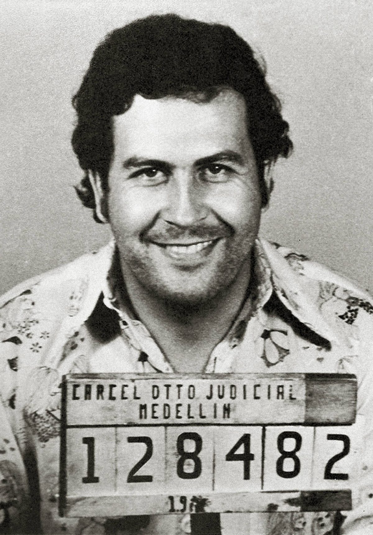 Pablo Escobar souriant sur sa photographie d'identité judiciaire prise à Medellín, matricule 128482.