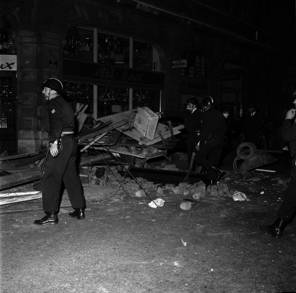 Des CRS casqués autour d'une barricade de pavés et de bois, rue de Metz, nuit du 11 au 12 juin 1968.
